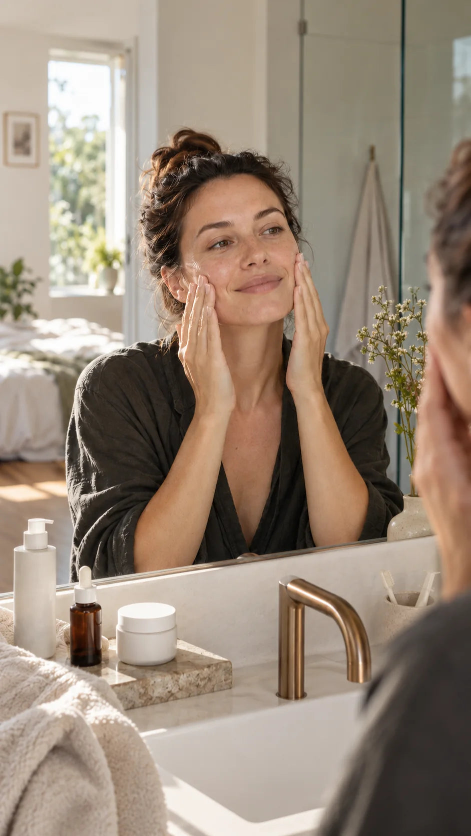 Femme appliquant un soin visage devant un miroir, version mobile du guide routine skincare.